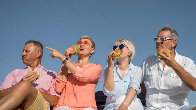 Elder couples together at the beach eating burgers