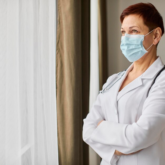 Женщина-врач центра выздоровления covid в медицинской маске смотрит в окно