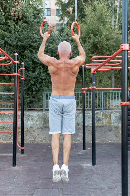 Elder man bodybuilding outdors full shot