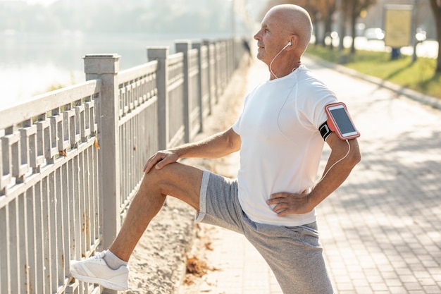 Elder man runner resting beside a fence