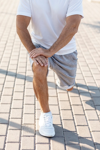 Elder man stretching on sidewalk