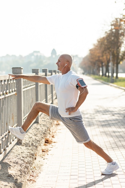 Elder runner stretching at a fence