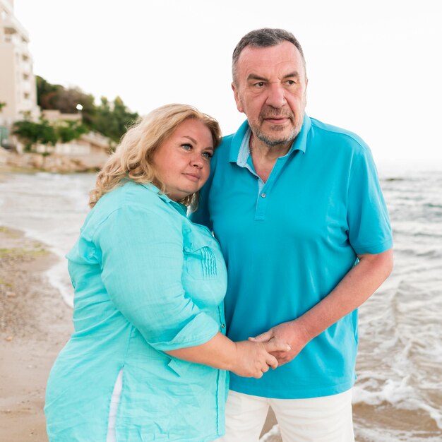 高齢者の観光客のカップルがビーチで抱擁