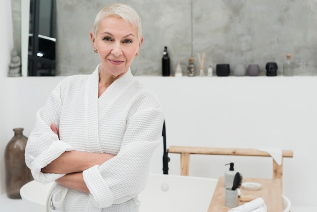 Elder woman in bathrobe smiling and posing with arms crossed