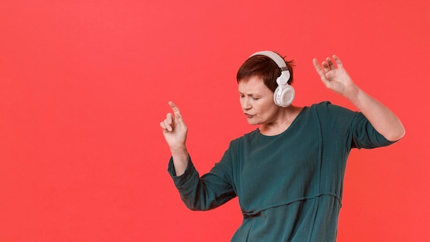 Бесплатное фото Пожилая женщина слушает музыку и танцы