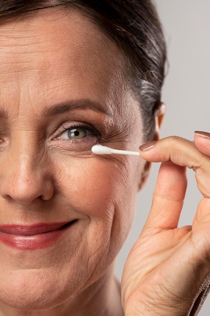 Elder woman removing make-up with cotton swab