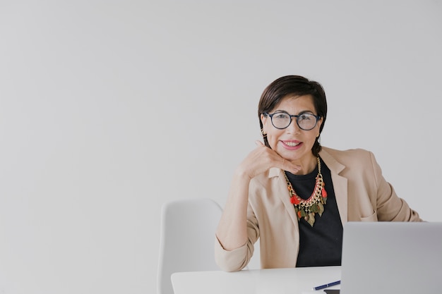 Free photo elder woman sitting on her office with copyspace