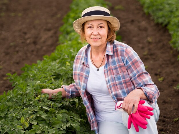 彼女の庭の植物の隣に滞在している年配の女性