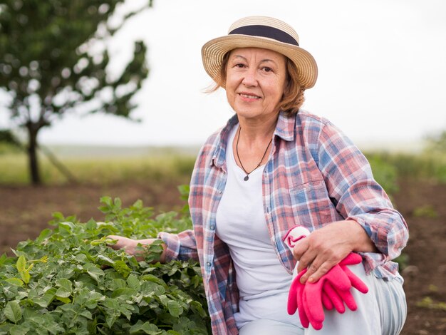 Elder woman staying next to a plant