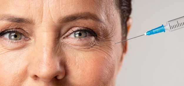Пожилая женщина с помощью инъекций от морщин вокруг глаз