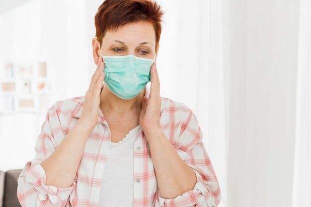 Free photo elder woman wearing medical mask at home