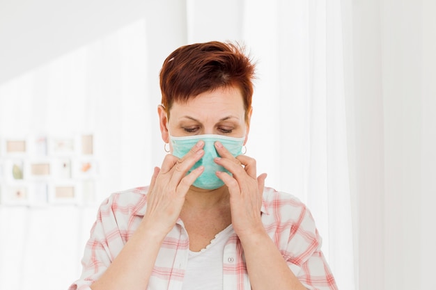 Elder woman wearing medical mask while at home