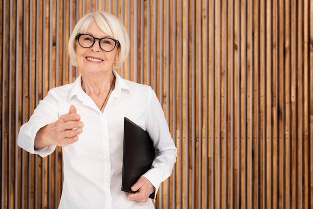 Elder woman with a clipboard on wooden background