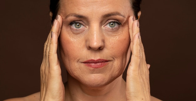 Elder woman with make-up on posing while holding her temples