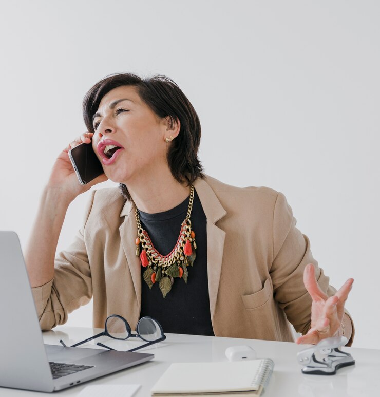 無料Photo 彼女のオフィスで電話で話しているネックレスを持つ年配の女性