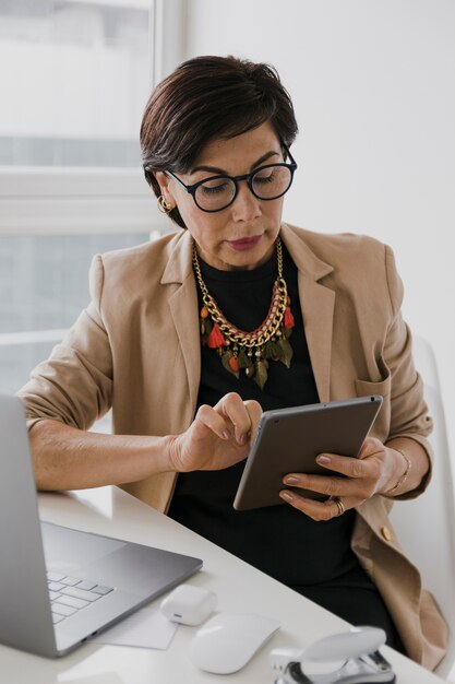 Elder woman with necklace touching a tablet