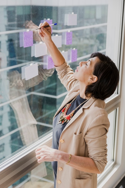 Free Photo elder woman writing with a pen on glass