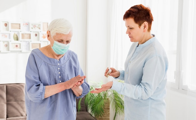 Foto gratuita donne anziane che disinfettano le mani mentre a casa