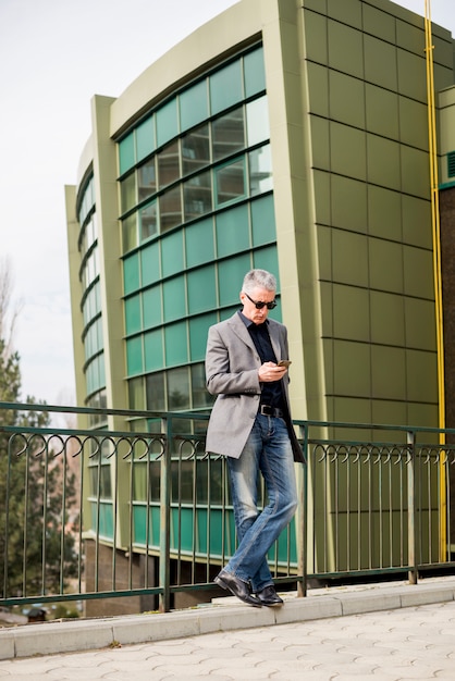 Free photo elderly businessman looking at mobile phone