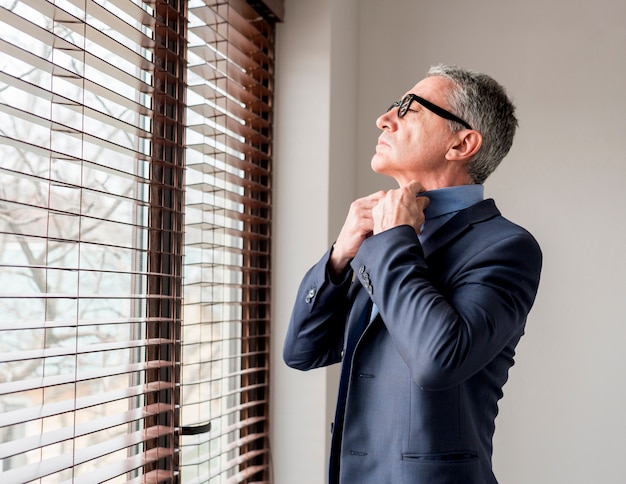 Free photo elderly businessman looking through the window