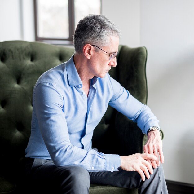 Elderly businessman posing on armchair