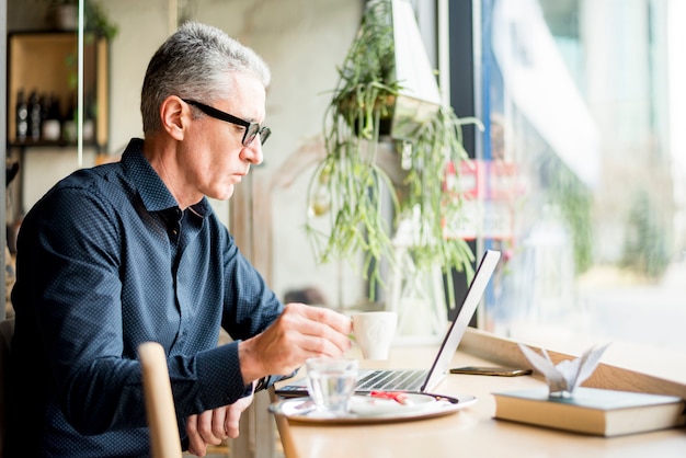 Elderly businessman working while having coffee