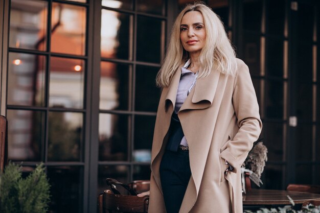 Elderly businesswoman in a coat outside the cafe