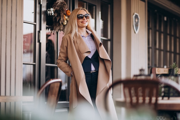 Free photo elderly businesswoman in a coat outside the cafe