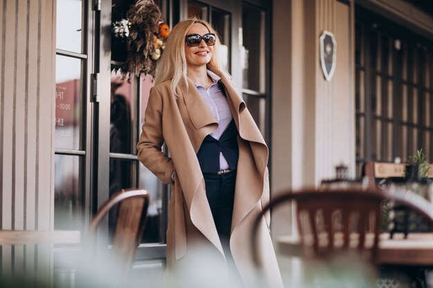 Elderly businesswoman in a coat outside the cafe