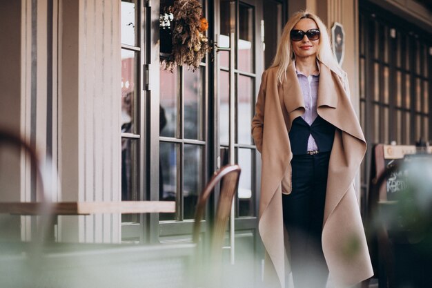 Elderly businesswoman in a coat outside the cafe