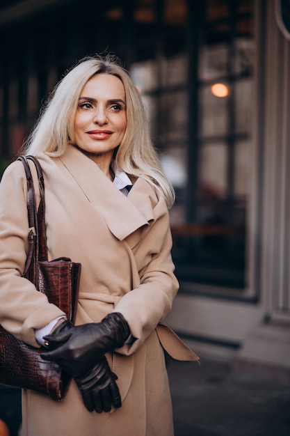 Elderly businesswoman in a coat wearing gloves in the street