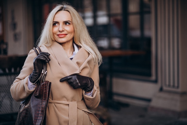 Elderly businesswoman in a coat wearing gloves in the street