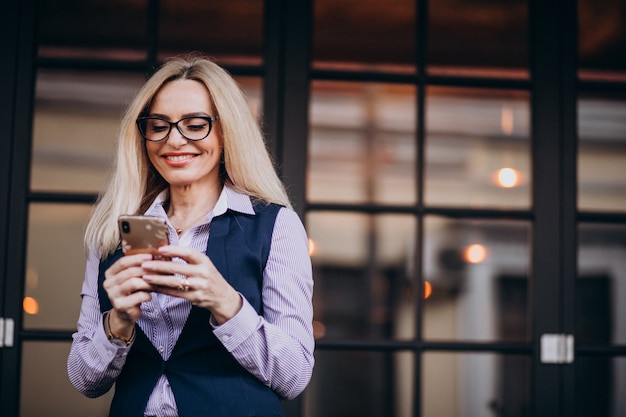 Elderly businesswoman outside the cafe using phone