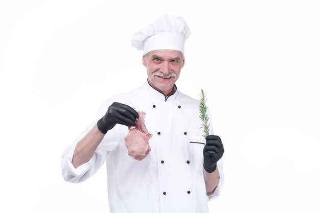 Elderly chef holds vegetation and meat