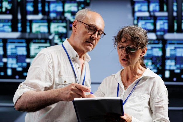 Free photo elderly computer scientists monitoring data center racks, optimizing them for data processing requirements of ai applications. supervisors oversee neural network server farm used for machine learning