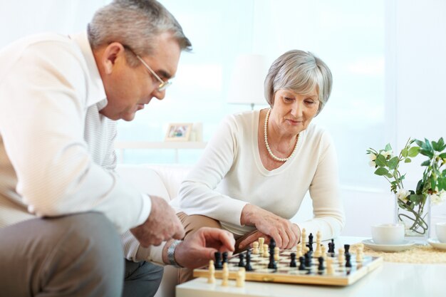 Elderly couple having fun with chess at home