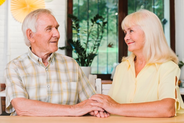 Free photo elderly couple holding each other hands sitting