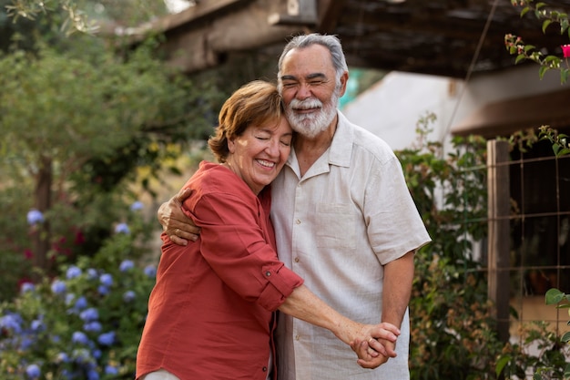 Пожилая пара романтически обнимает друг друга в своем загородном саду