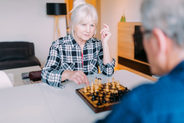 Elderly couple playing chess in retirement home