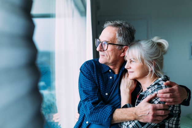 Elderly couple in retirement home looking out of window