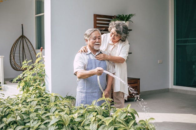 Elderly couple watering a flower in home garden