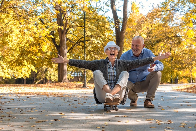 Пожилая пара с женщиной, сидящей на коньках в парке