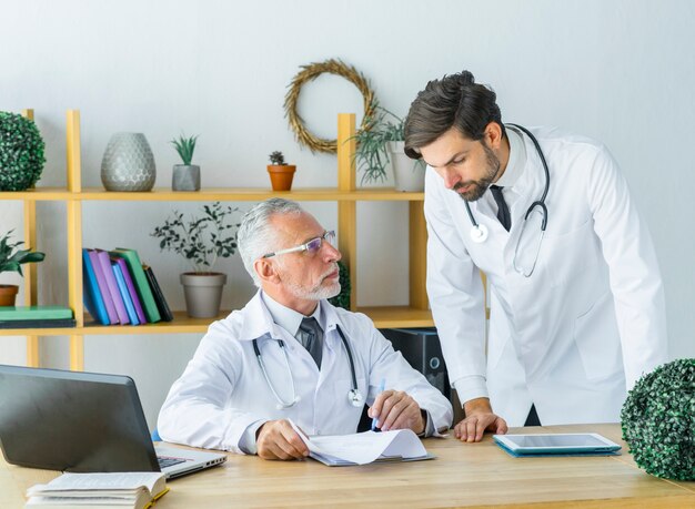 Elderly doctor showing notes to young colleague