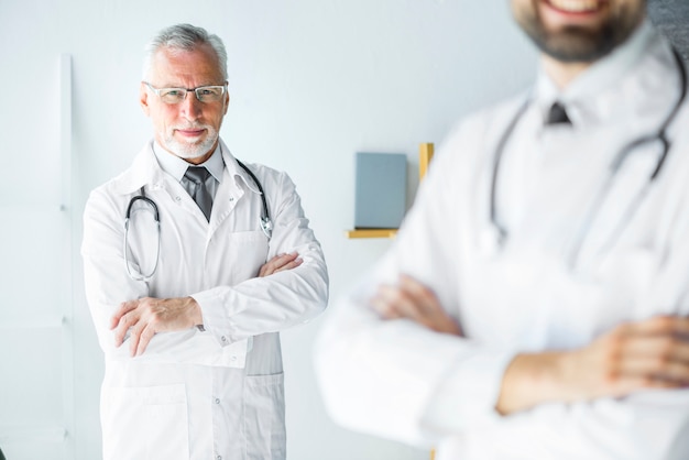 Elderly doctor standing behind anonymous colleague