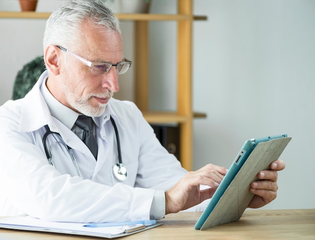 Elderly doctor using tablet in office