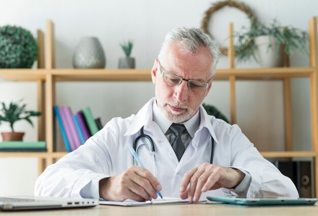 Elderly doctor writing prescription