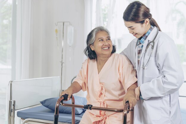 Elderly female smiling with young female doctor visiting senior patient woman at hospital ward