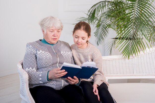 Elderly grandma reading with her granddaughter
