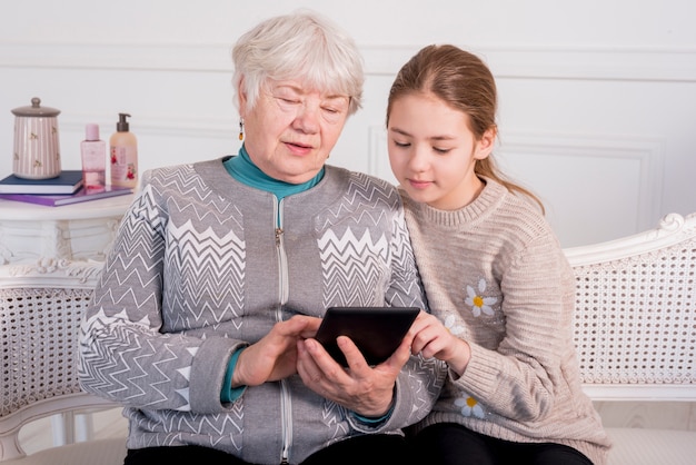 Free photo elderly grandma reading with her granddaughter