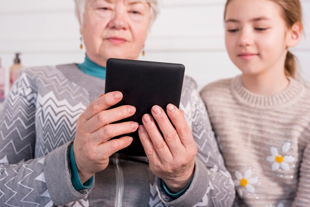 Elderly grandma reading with her granddaughter